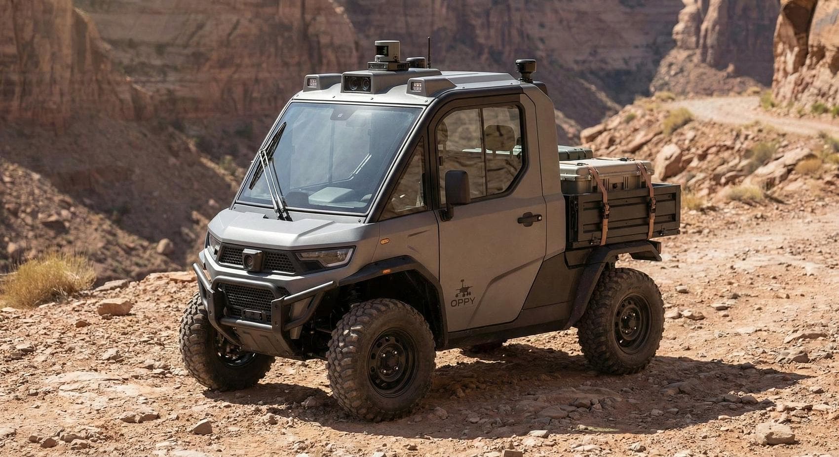 OPPY, a grey utility vehicle with an enclosed cab and cargo bed, parked on a desert canyon trail